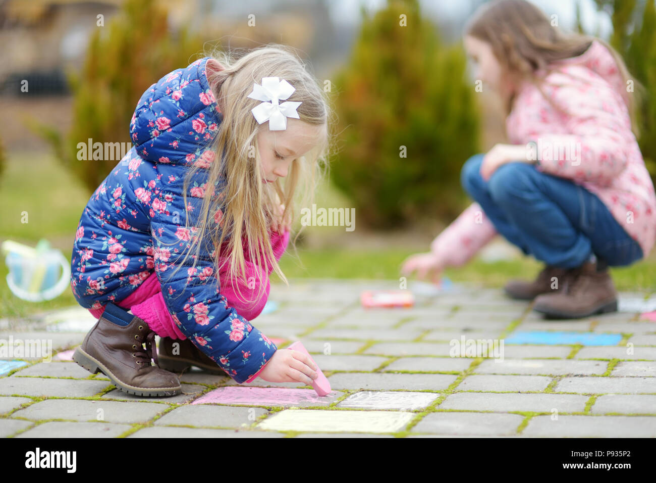 Two happy children drawing with colorful chalks on a sidewalk. Summer ...