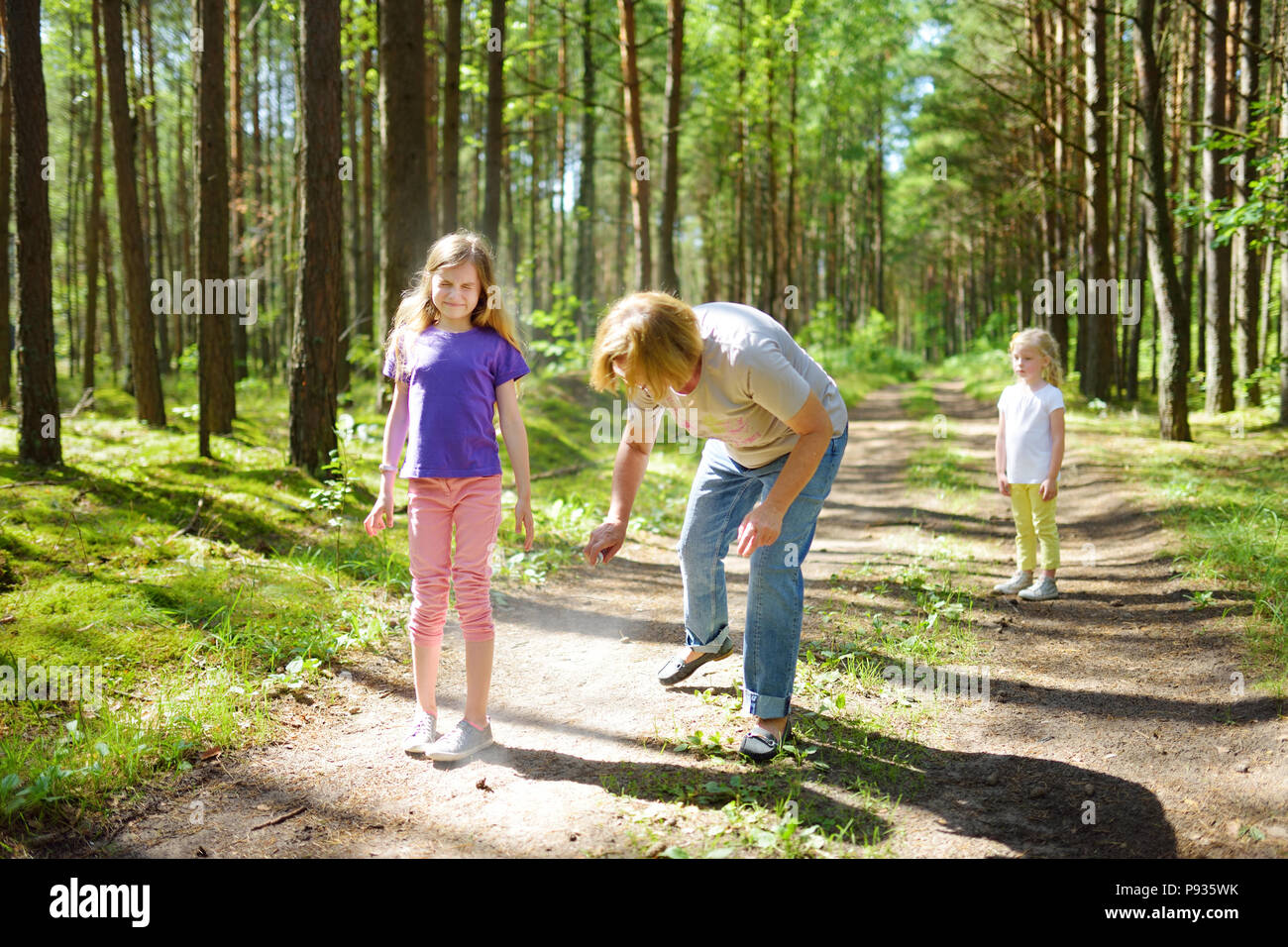 Middle age woman applying insect repellent to her granddaughter before forest hike beautiful summer day. Protecting children from biting insects at su Stock Photo