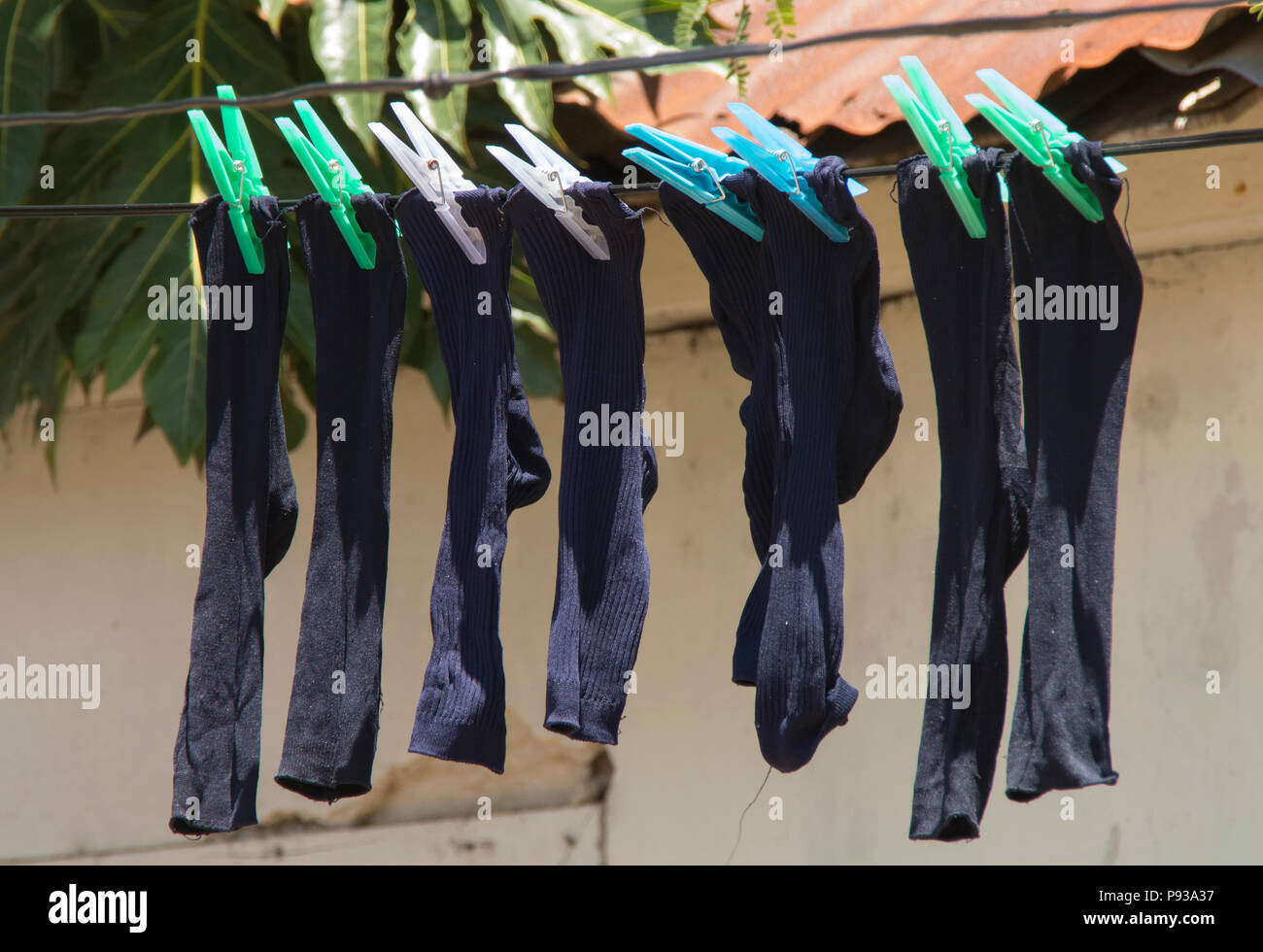 Old red socks hanging on rope attached with clothespins to dry