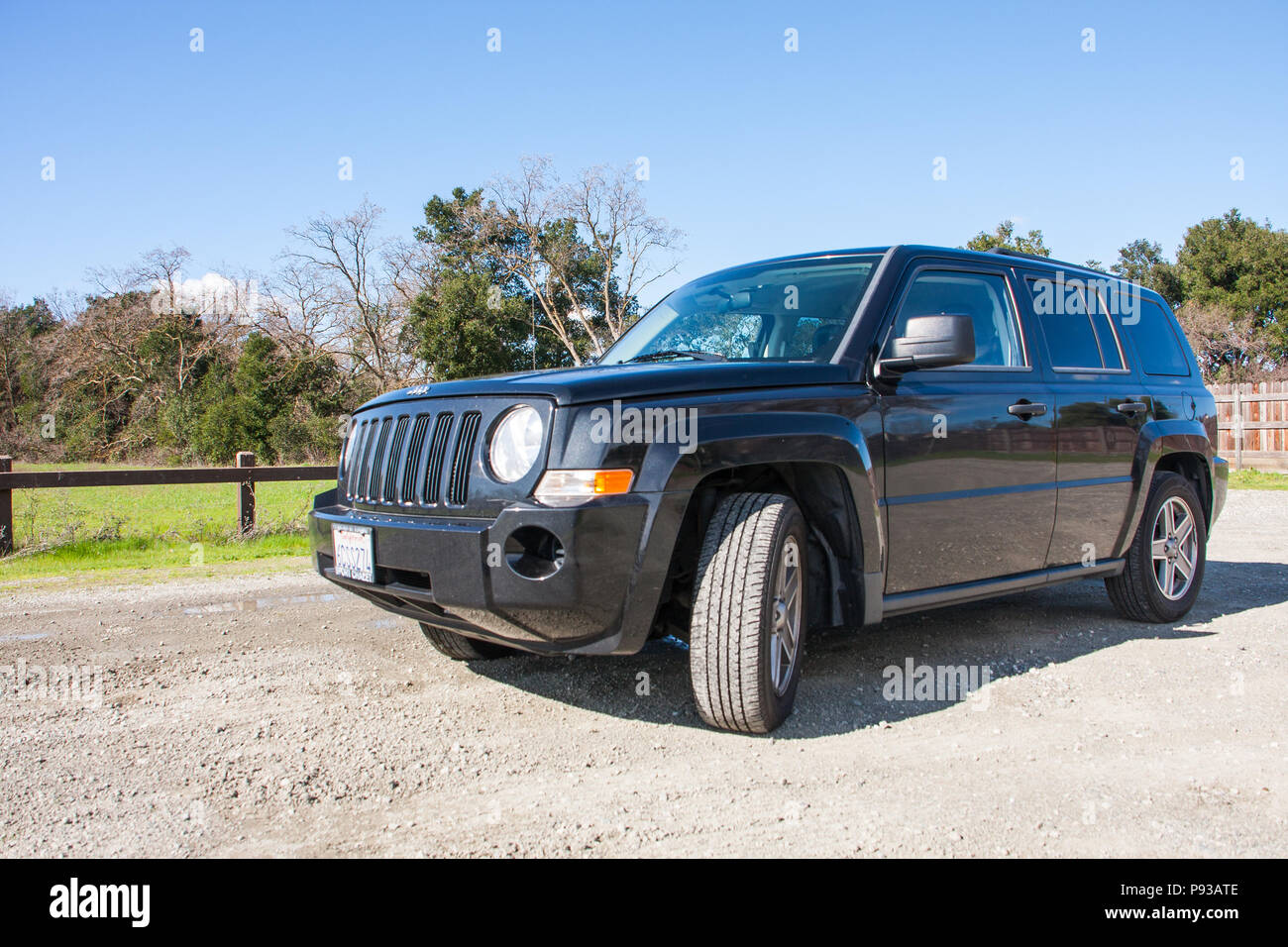Black Jeep Patriot SUV (sport utility vehicle) in outdoor natural background with California license plate - side view Stock Photo