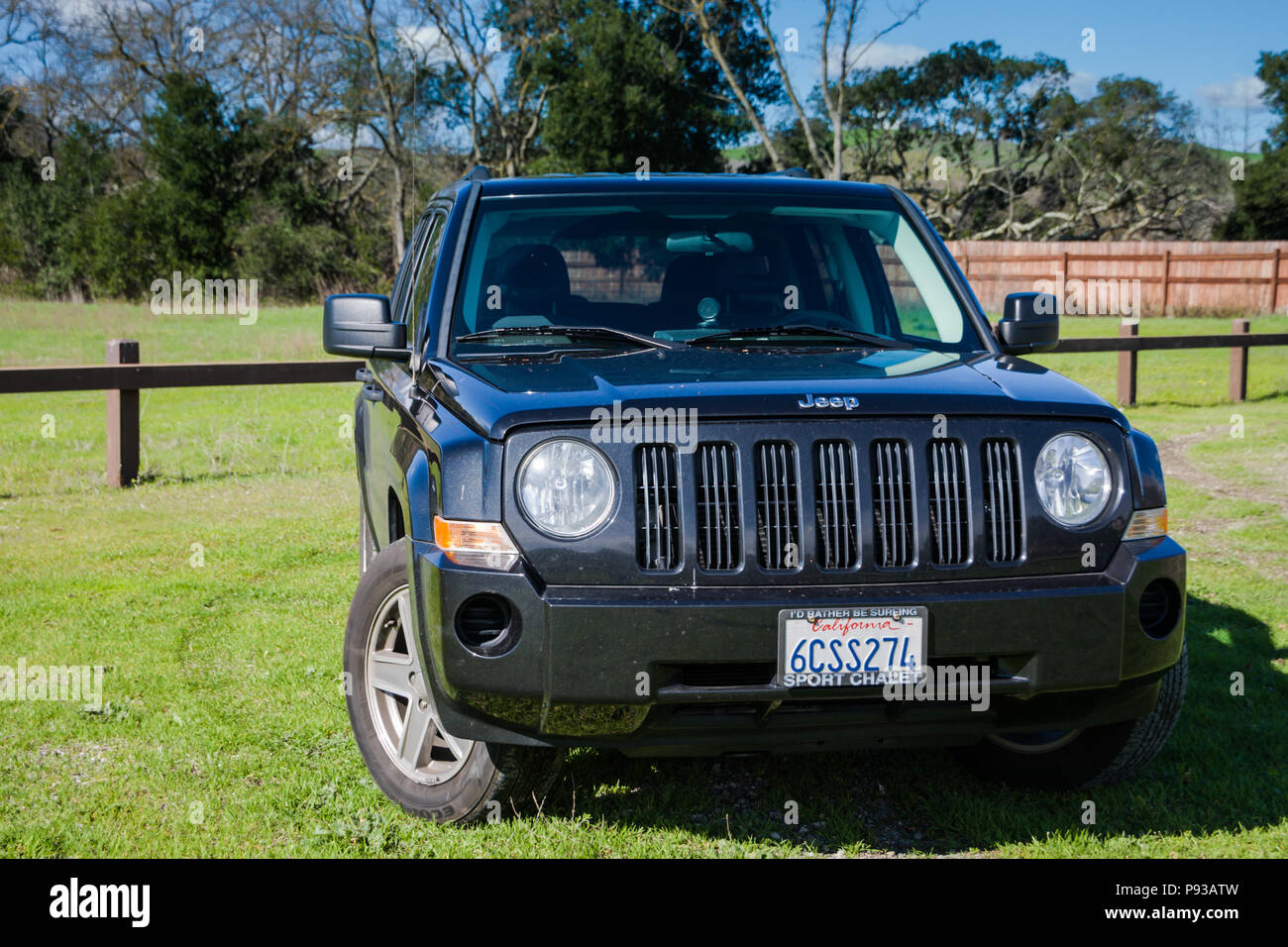 Black Jeep Patriot SUV (sport utility vehicle) in outdoor natural background with California license plate - front and side view Stock Photo
