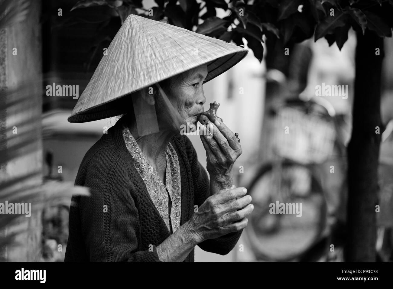 An elderly Vietnamese woman plays a OCARINA on the streets of HOI AN - CENTRAL VIETNAM Stock Photo