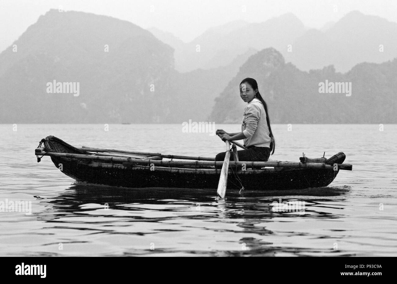 A young girl rows her boat on the waters of HALONG BAY - VIETNAM Stock Photo