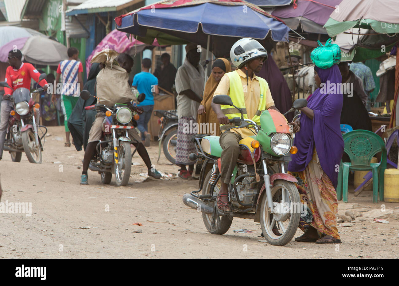 Kakuma, Kenya - Street scene with people and motorcycles. Motorcycle traffic on a busy unpaved road. Stock Photo