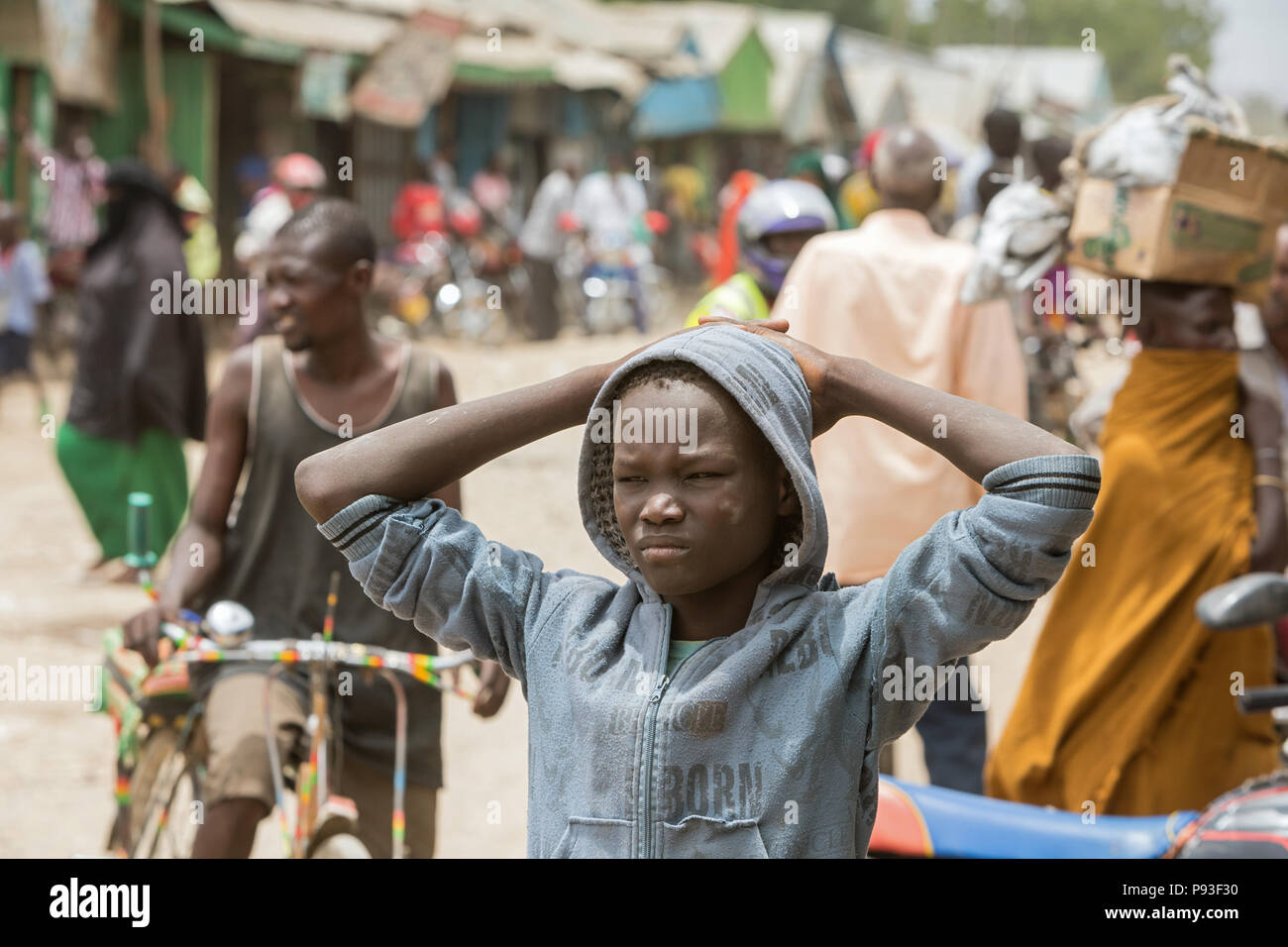 Kakuma, Kenya - Street scene with people on a busy unpaved road. Portrait of a thoughtful boy. Stock Photo