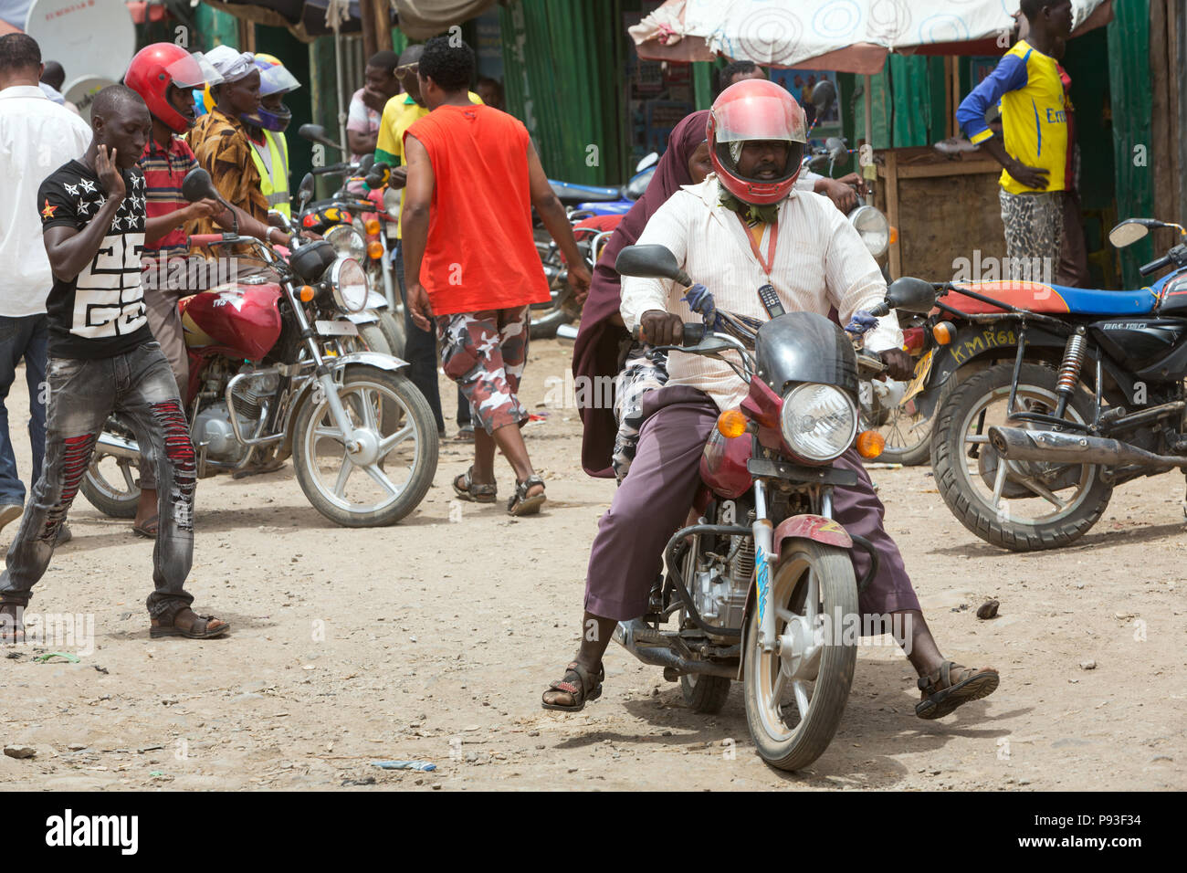 Kakuma, Kenya - Street scene with people and motorcycles. Motorcycle traffic on a busy unpaved road. Stock Photo