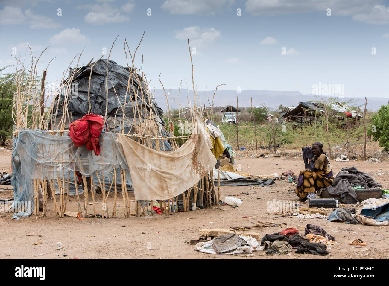 Kakuma, Kenya - On the edge of the refugee camp Kakuma. A woman is lost in front of her hut, covered with old plastic tarpaulins. Stock Photo