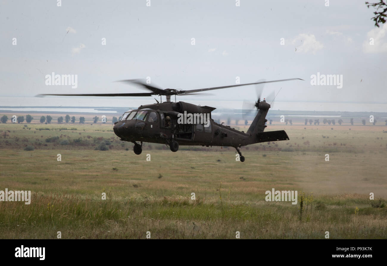 U.S. Soldiers assigned to the 2nd General Support Aviation Battalion, 4th Aviation Regiment, 4th Combat Aviation Brigade, 4th Infantry Division, fly into a landing zone in their UH-60 Blackhawk while performing an air assault training at Mihail Koglniceanu Air Base, Romania, July 10, 2018. The Soldiers of 2nd GSAB are conducting similar training in multiple locations throughout Europe in support of Atlantic Resolve, a U.S. endeavor to fulfill NATO commitments by rotating U.S.-based units throughout the European theater to deter aggression against NATO allies and partners in Europe. (U.S. Army  Stock Photo