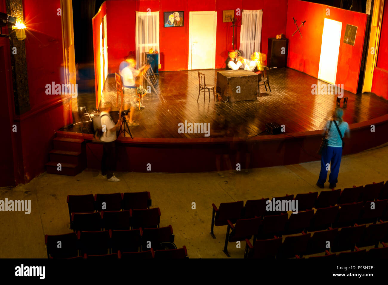 Long exposure photo, photographers are taking photo together of young woman posing in empty theater stage. Stock Photo