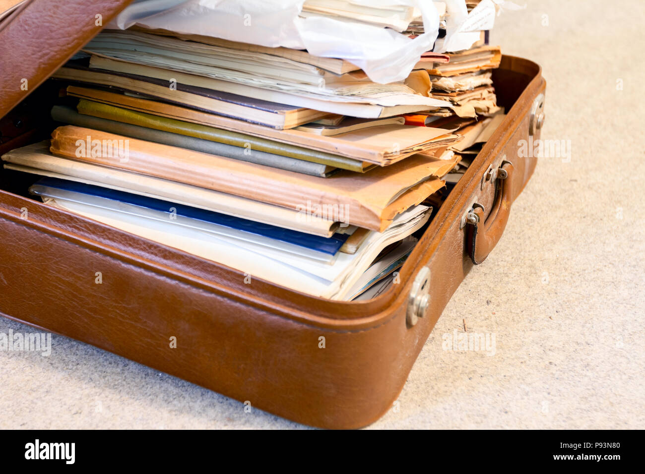 Old fashioned suitcase made of leather is full of folders, papers and