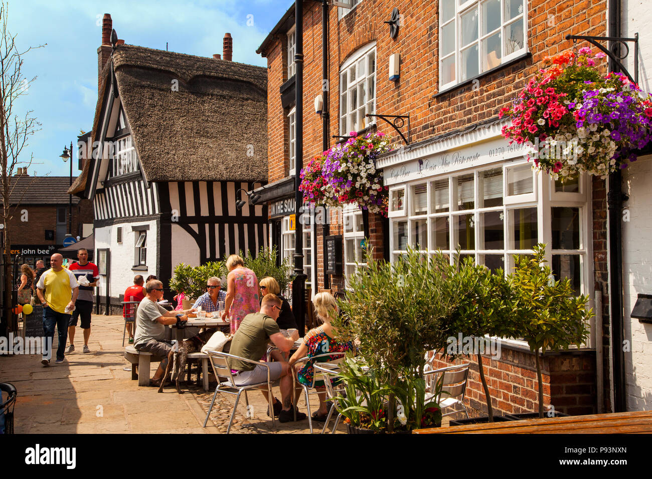 People men and women enjoying the summer sunshine eating and drinking outside at pavement cafe in the market town of Sandbach in Cheshire England UK Stock Photo