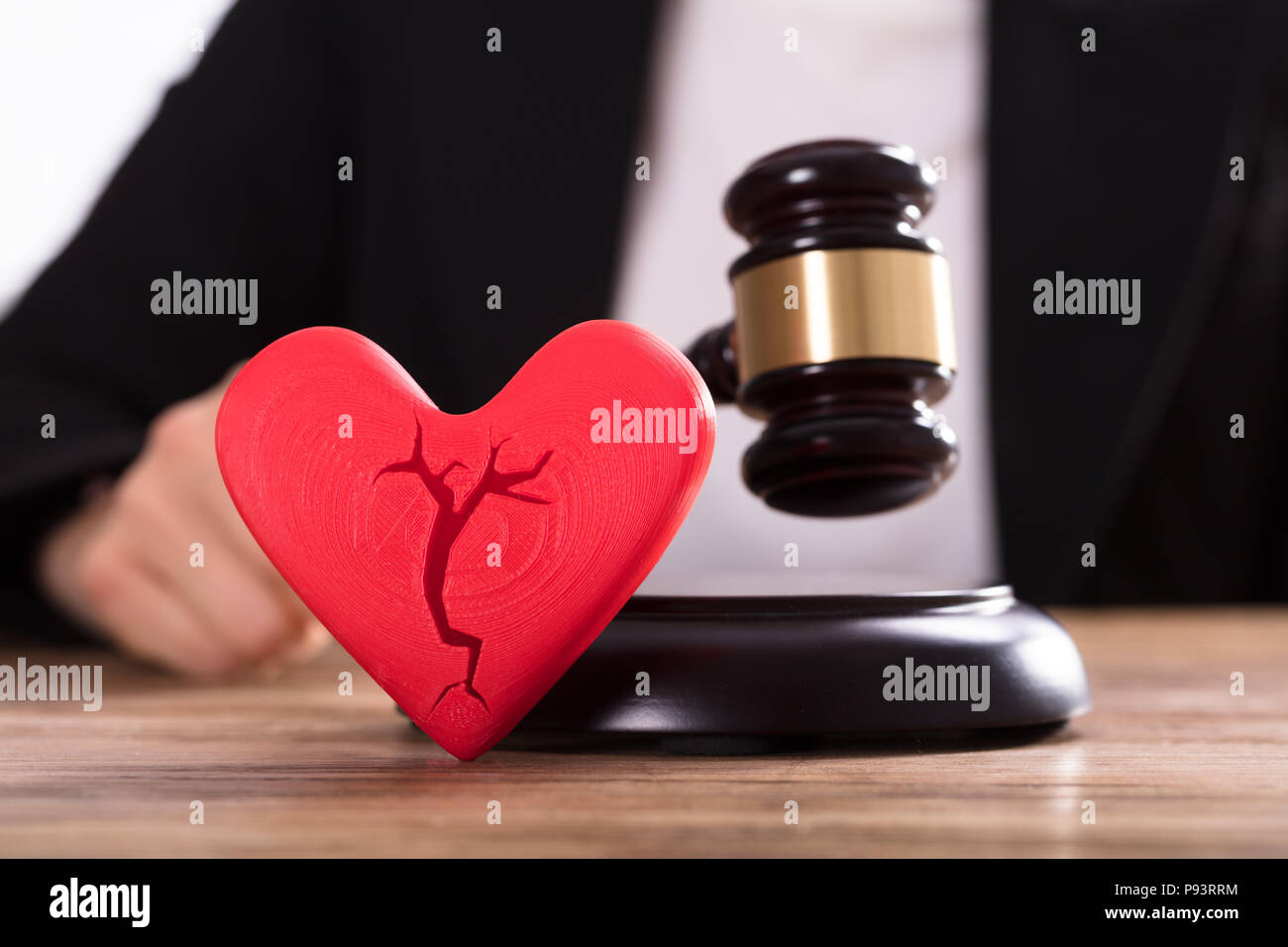 Close-up Of A Broken Red Heart In Front Of Judge Striking Mallet Stock Photo