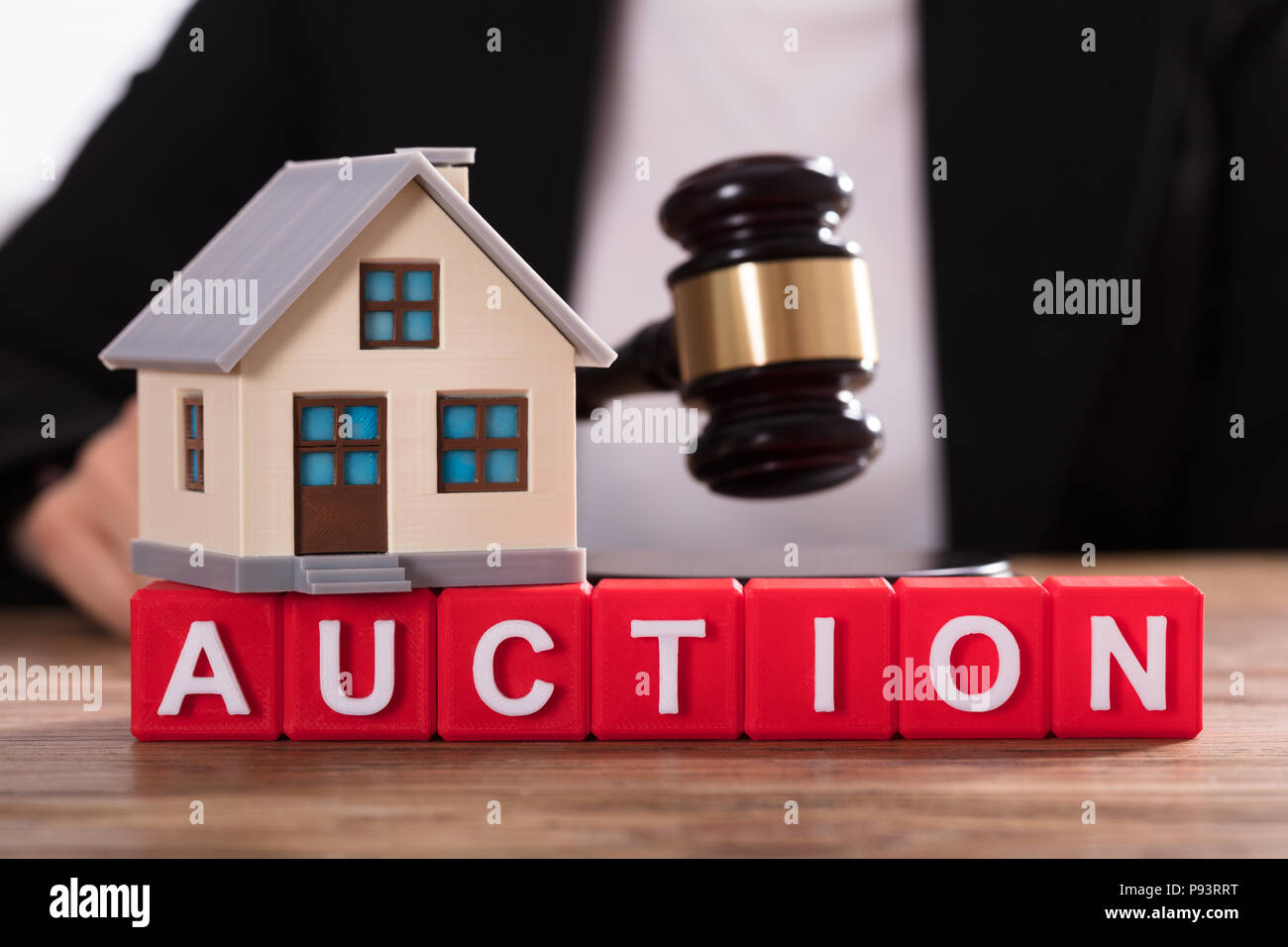 House Model Over Auction Cubic Blocks In Front Of Judge Striking Gavel Stock Photo
