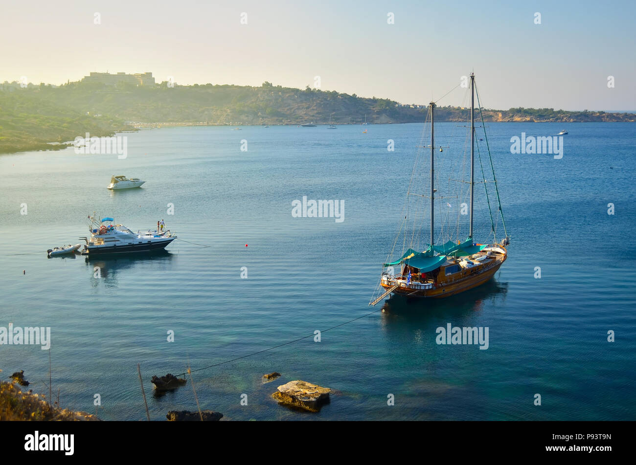 Wooden yacht and some boats are anchored in a beautiful sea bay on a sunset. Konnos bay, Cyprus. Stock Photo
