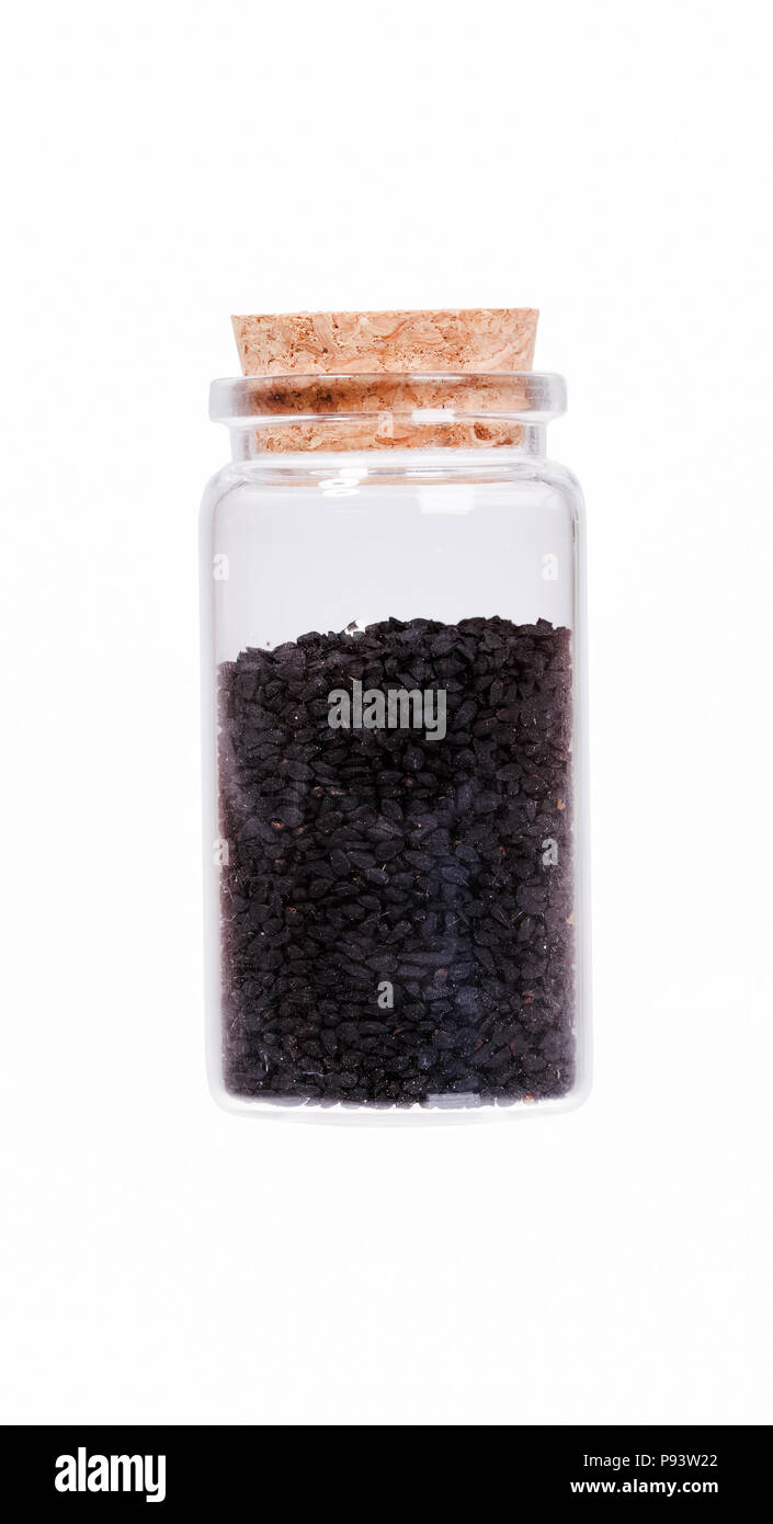 Nigella or Black cumin in a glass bottle with cork stopper, isol Stock Photo