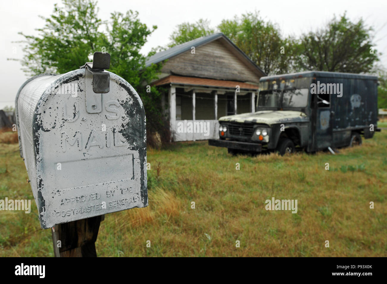 A weathered mailbox stands near an abandoned vehicle and home on a rural property in the Route 66 town of Texola, Oklahoma. Stock Photo