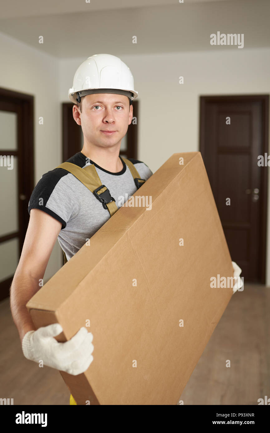 Man in hard hat hold cardboard box inside of house Stock Photo