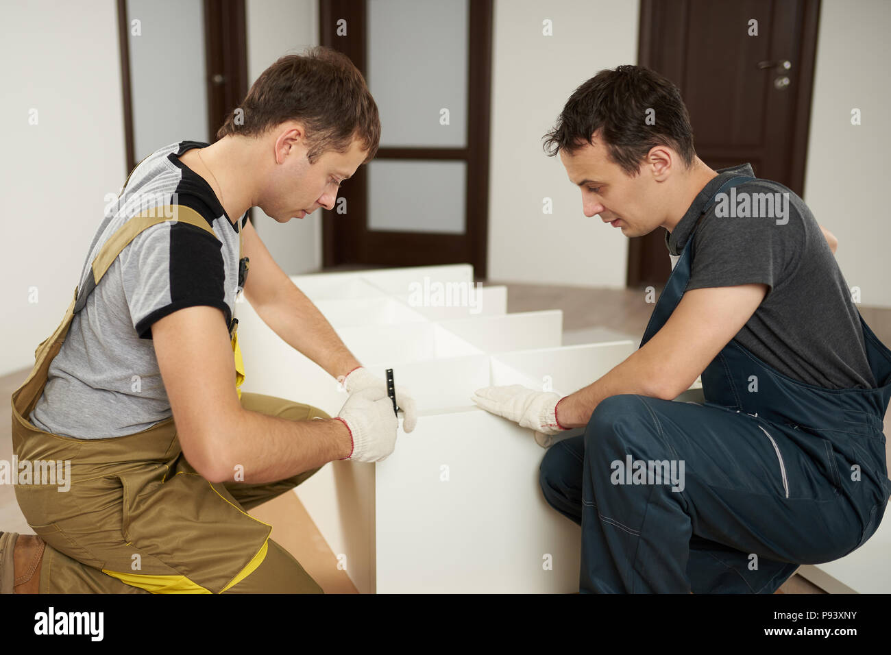 Service of assembly furniture. Two carpenters work on assemble wardrobe Stock Photo