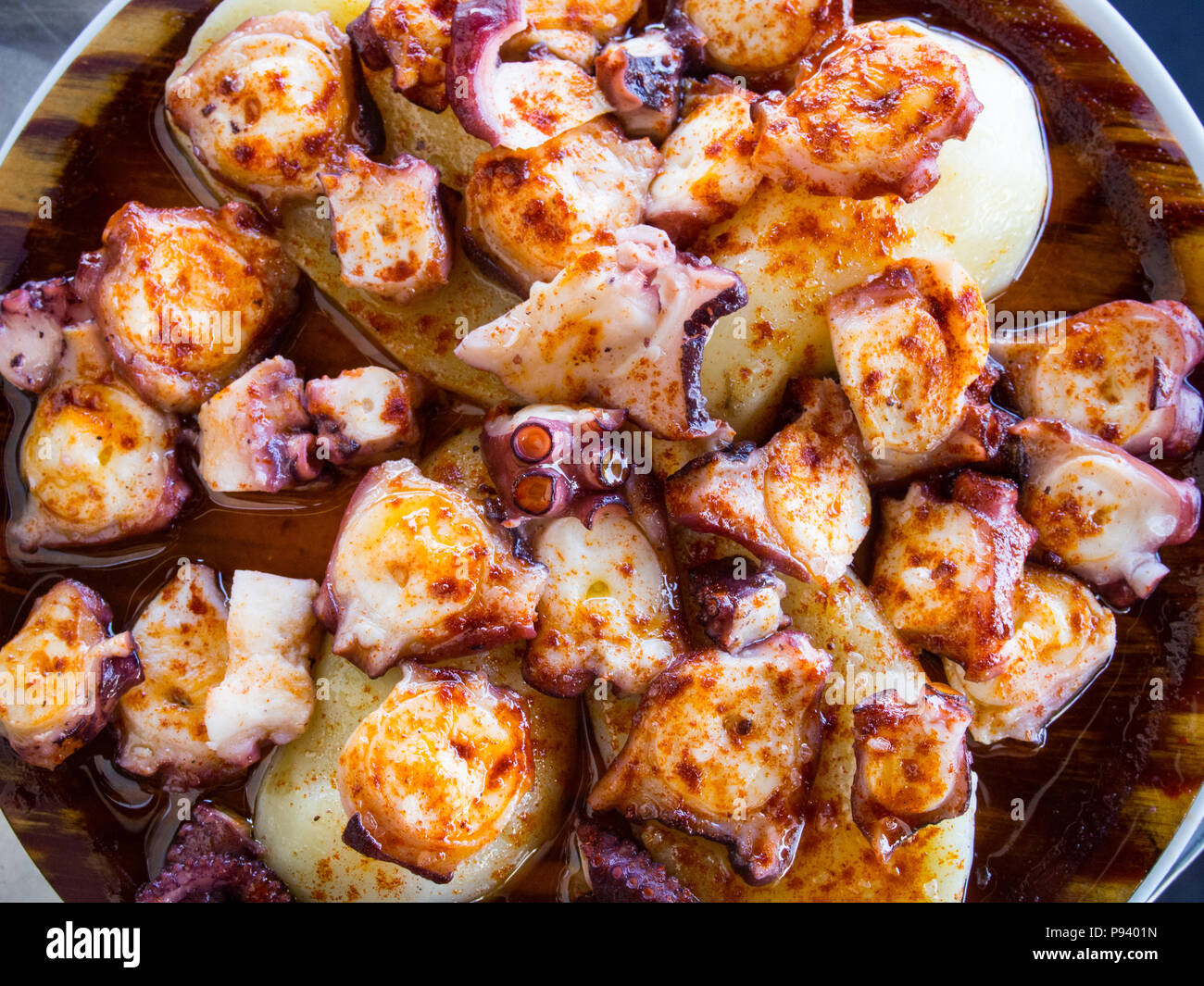 Octopus and potatoes cooked with paprika and olive oil on wood plate.  Galician food Stock Photo