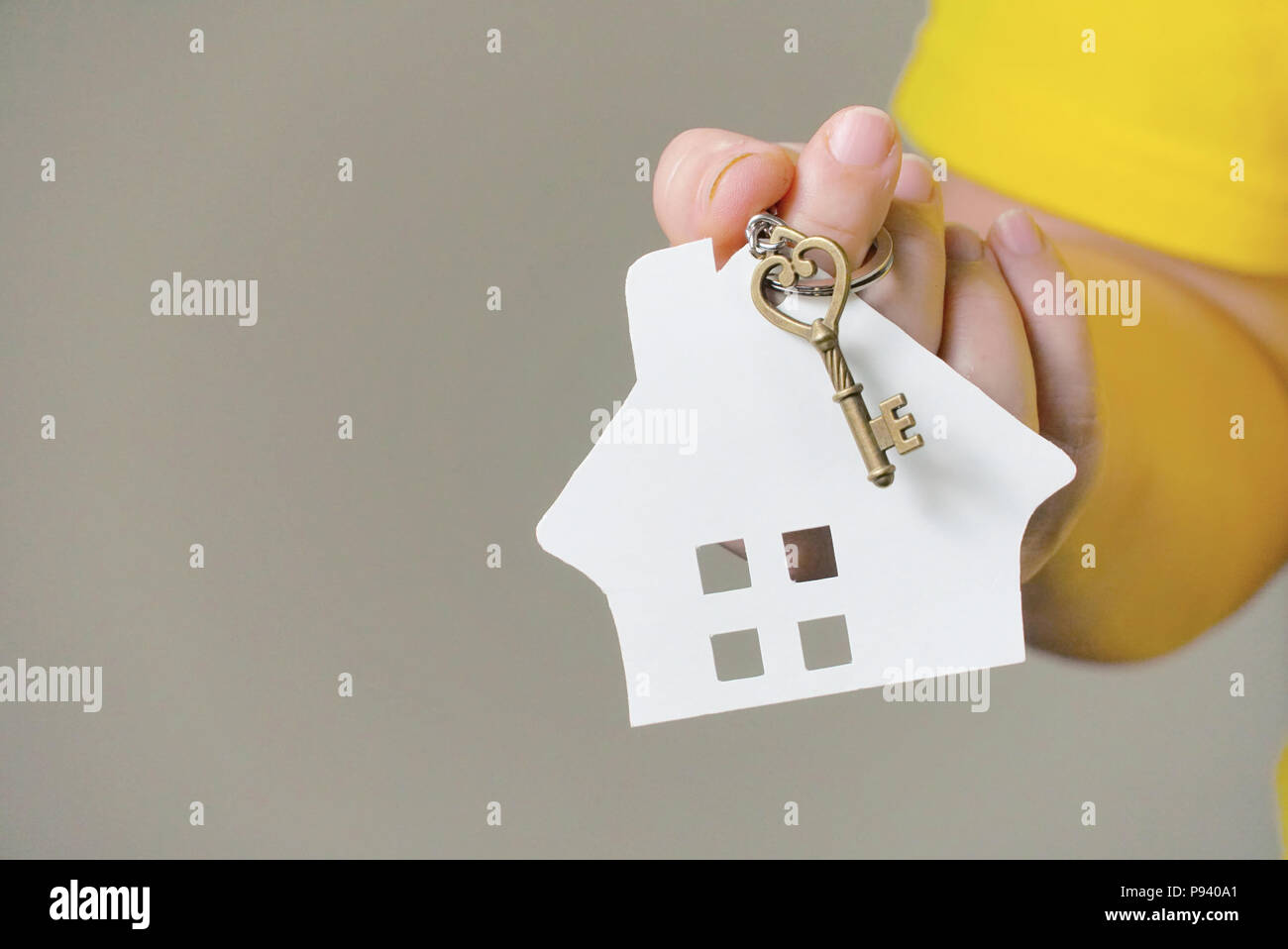 House owner wear yellow shirt holding house key on hand. Stock Photo