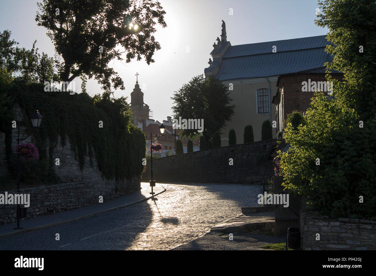 Photo of old cozy paving stone street in the sunny summer morning and backlight. Stock Photo