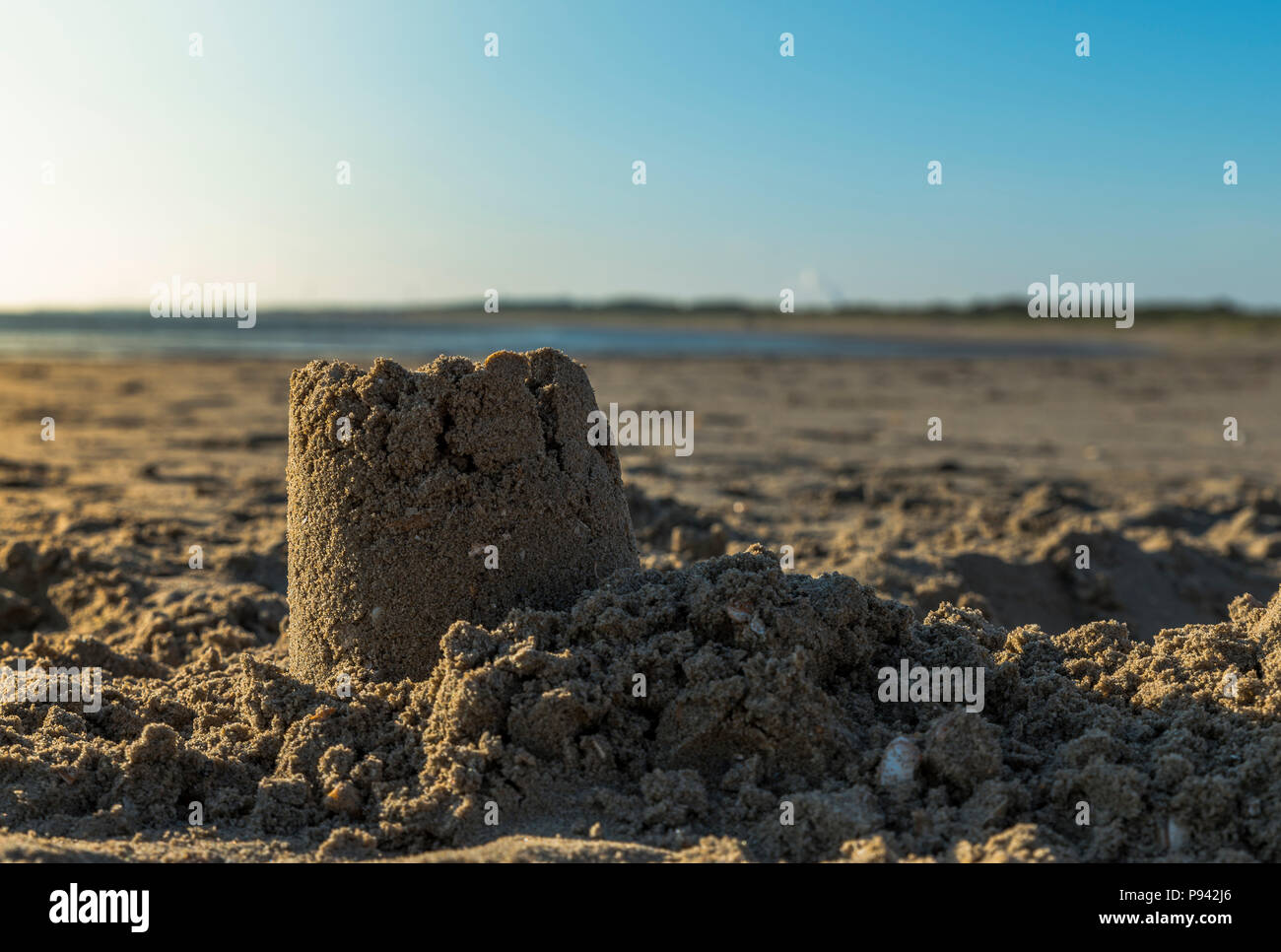 sandcastle at the beach with low sunset at the background Stock Photo