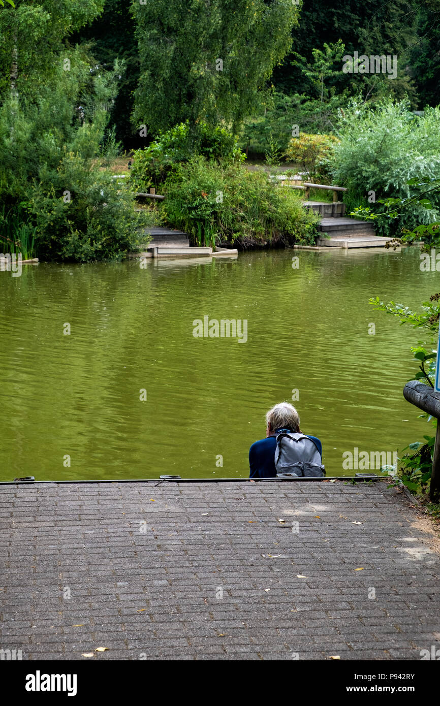 Man sitting on a jetty on the river edge Stock Photo