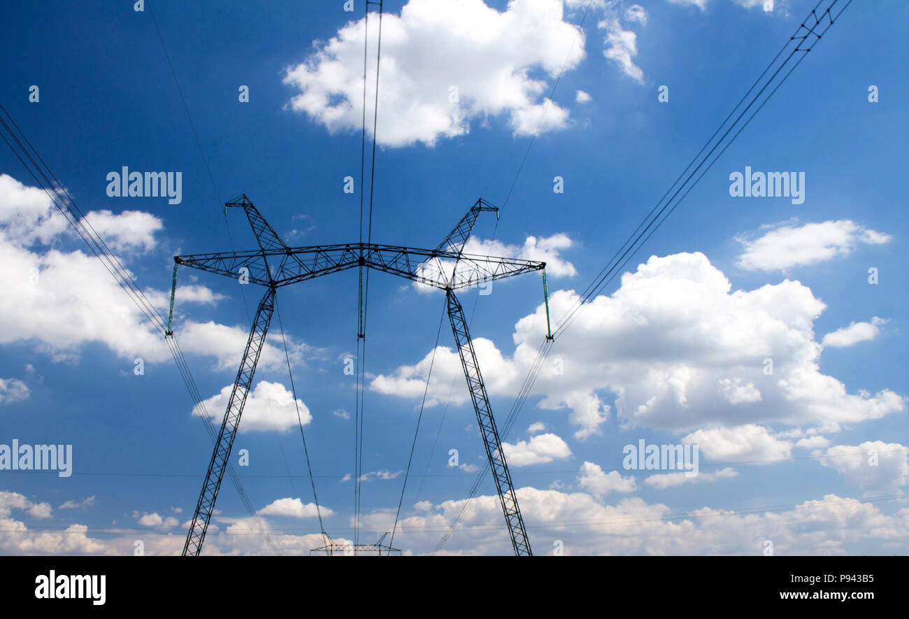Photo of power transmission tower. High voltage pillar on blue sky background. Stock Photo