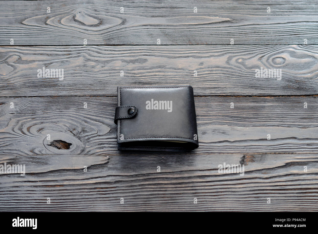 Black leather elegance men's wallet on dark wooden background. Single object. Stock Photo