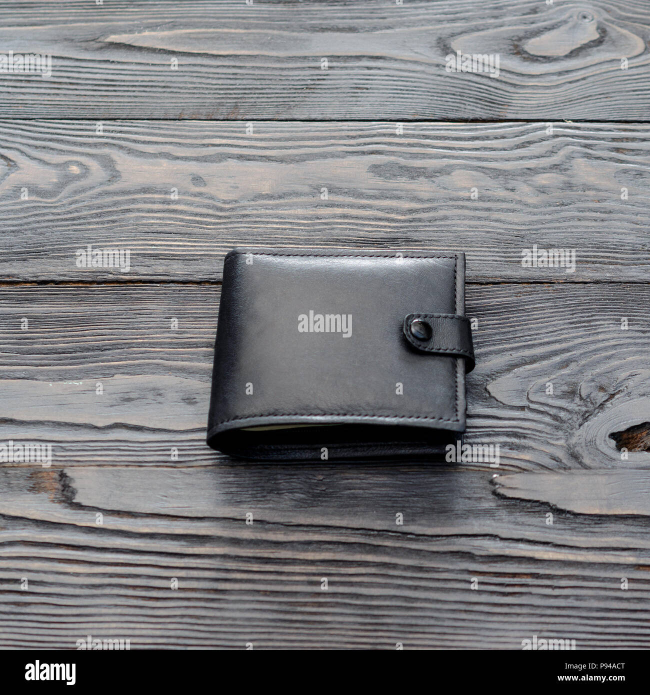 Black leather elegance men's wallet on dark wooden background. For instagram format. Square. Single object. Stock Photo