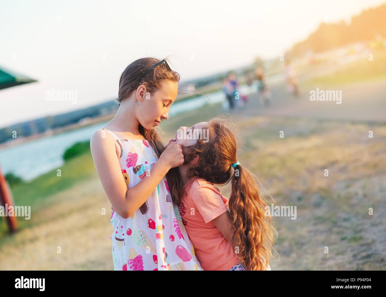 Two Happy little girls having fun and embracing  at meadow at summer day Stock Photo