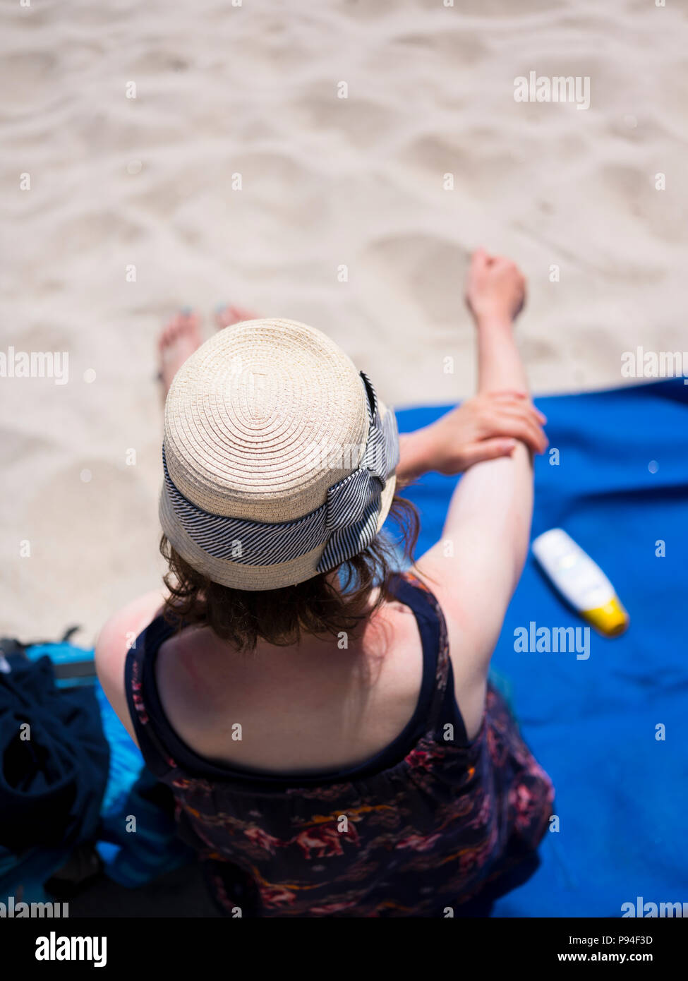 A woman applying suncream on a sunny day. Stock Photo
