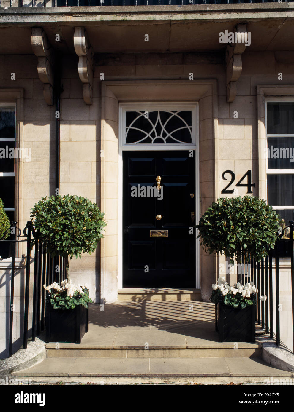 clipped bay trees in pots on either side of black front door on