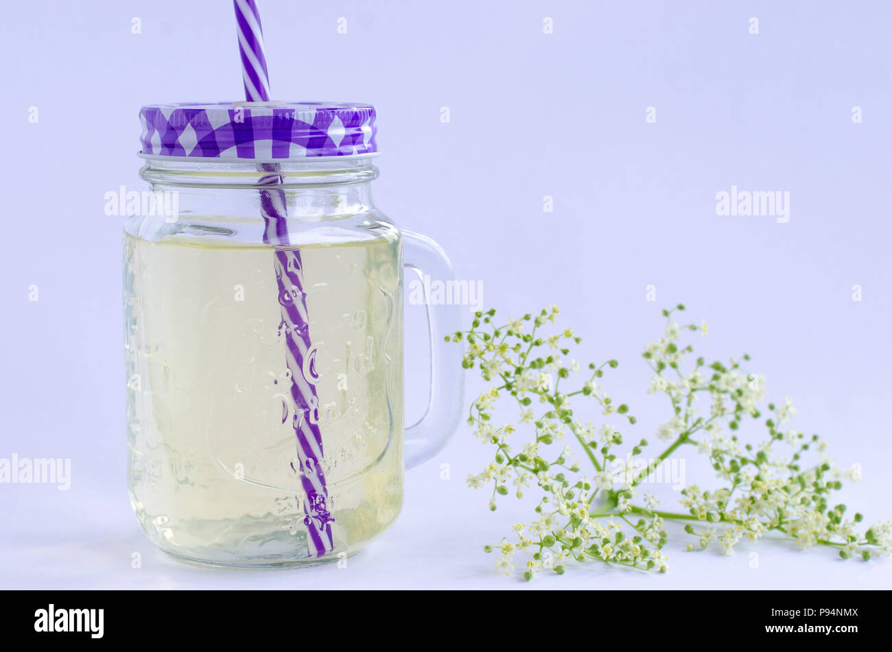 The making of elderflower lemonade. A ready-made drink of elderflower lemonade with elderflower beside it with white background. Stock Photo