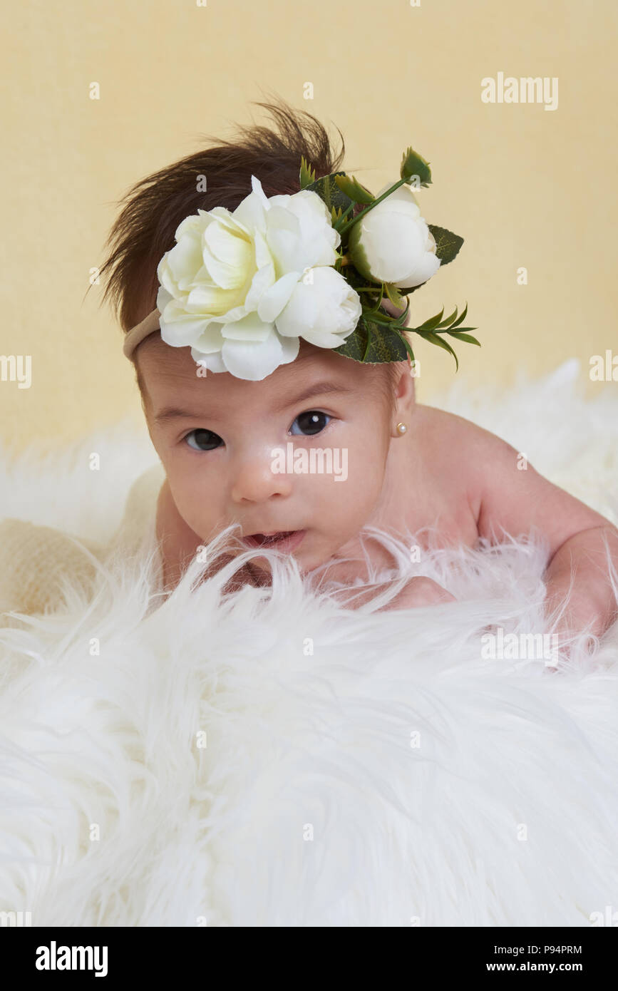 Baby girl with flower bow on yellow blurred background Stock Photo