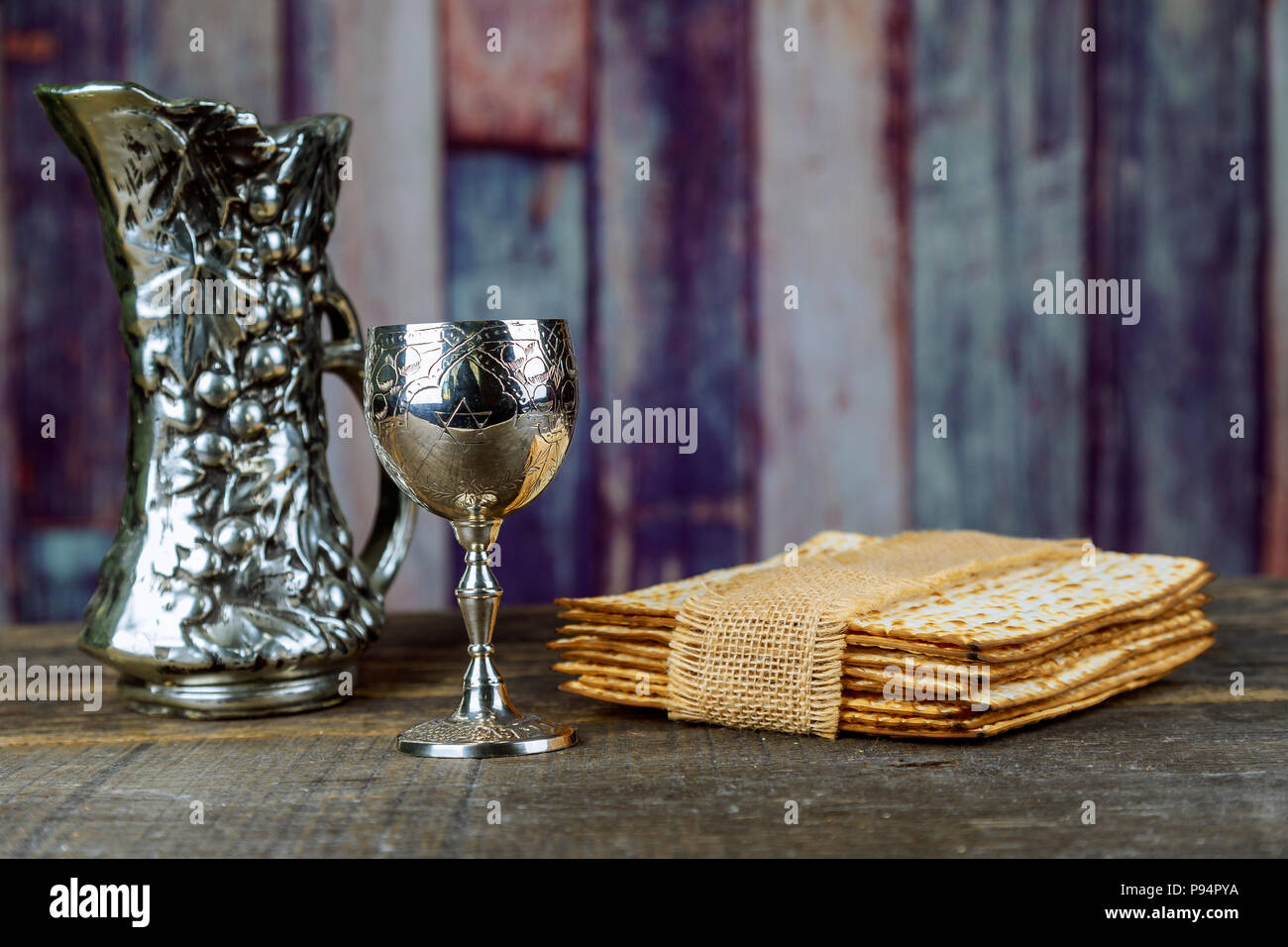 Red kosher wine with matzah a Passover Haggadah on a vintage wood background presented seder kiddush cup of wine Stock Photo