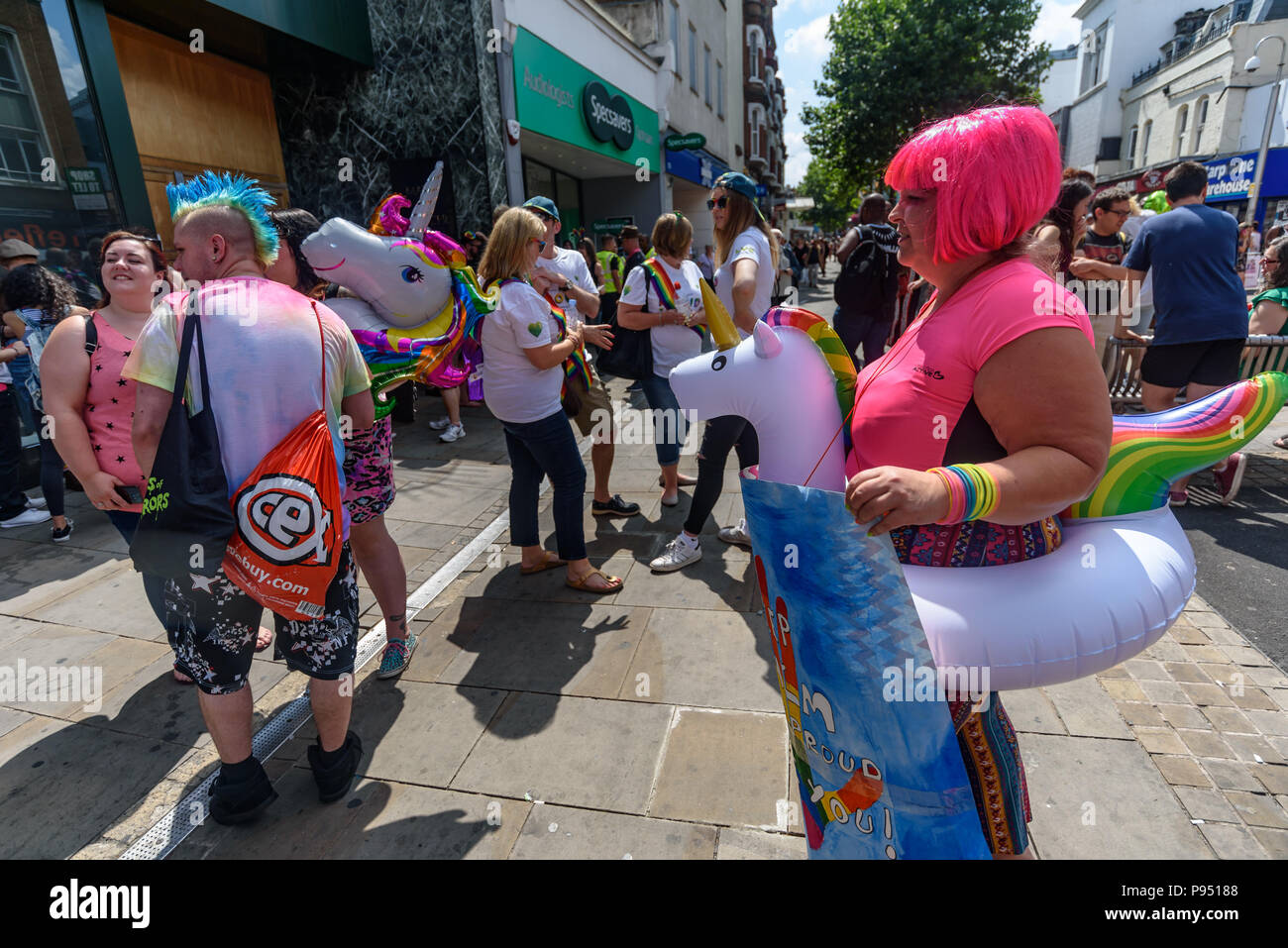 London, UK. 14th July 2018. People, including two unicorns, wait for  Croydon Pride procession to start. Several hundred people paraded through the centre of Croydon on their way to the third Croydon Pridefest, sponsored by Croydon Council, in Wandle Park. Many were in colourful dress and there were banners, flags, placards, posters and unicorns. The free festival aims to promote LGBT+ equality and diversity in Croydon, and is London's second largest Pride festival. Following the disruption by anti-Trans activists at London Pride, the parade gave the Trans People Across London (TRANSPALS) bann Stock Photo