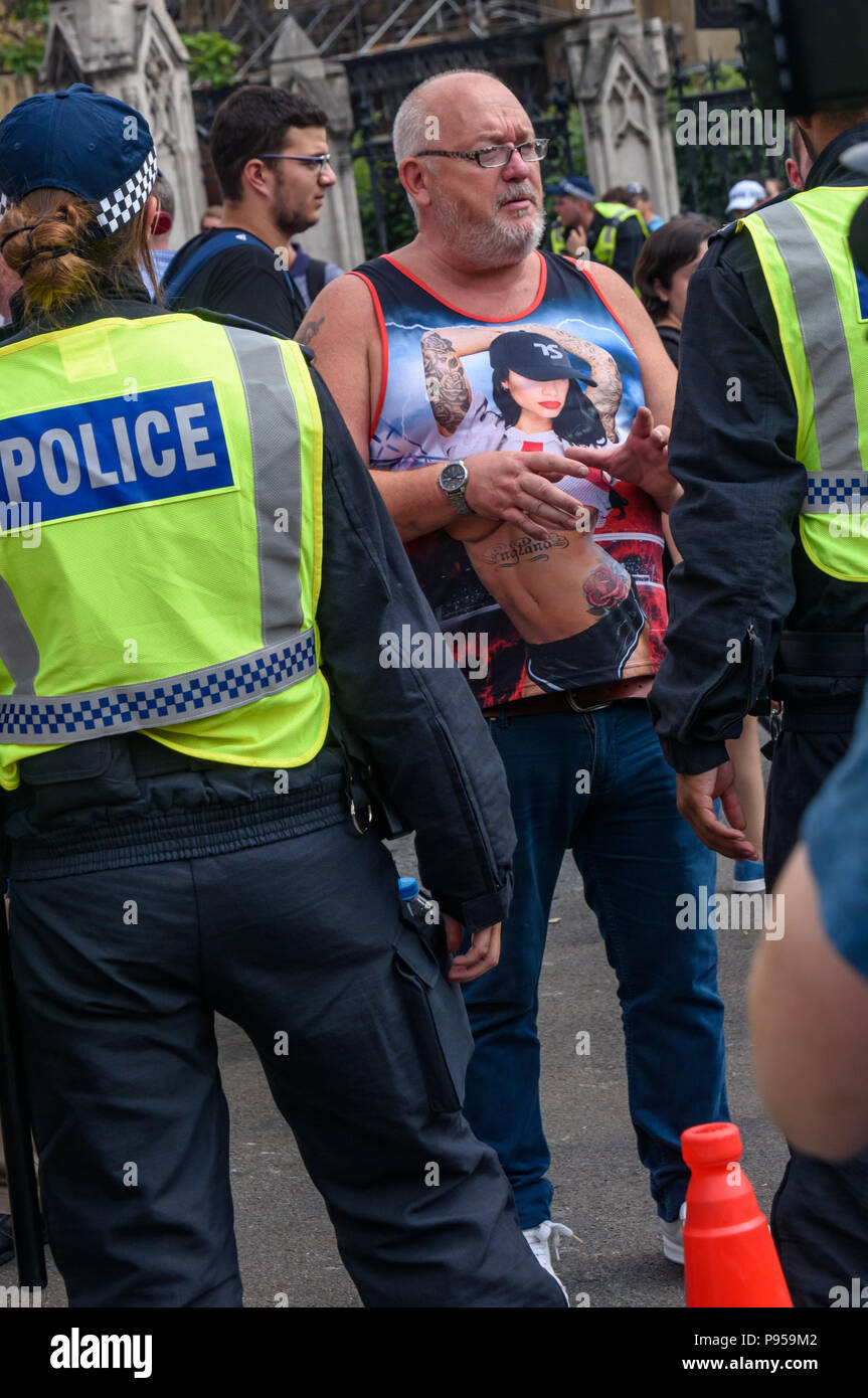 London, UK. 14th July 2018. Police in Bridge Street hold back a man wearing a t-shirt shoing a young female England supporter showing off her tatoos who they think is a right-wing football hooligan who has come to harass the anti-fascists protesting against the 'Free Tommy' protests over the jailing of Tommy Robinson for contempt of court for actions which could have stopped the trial of a grooming gang - an offence to which he pleaded guilty. The police stopped most of them and the anti-fascists stood their ground and repelled the few who evaded the police until police removed them.  Peter Ma Stock Photo