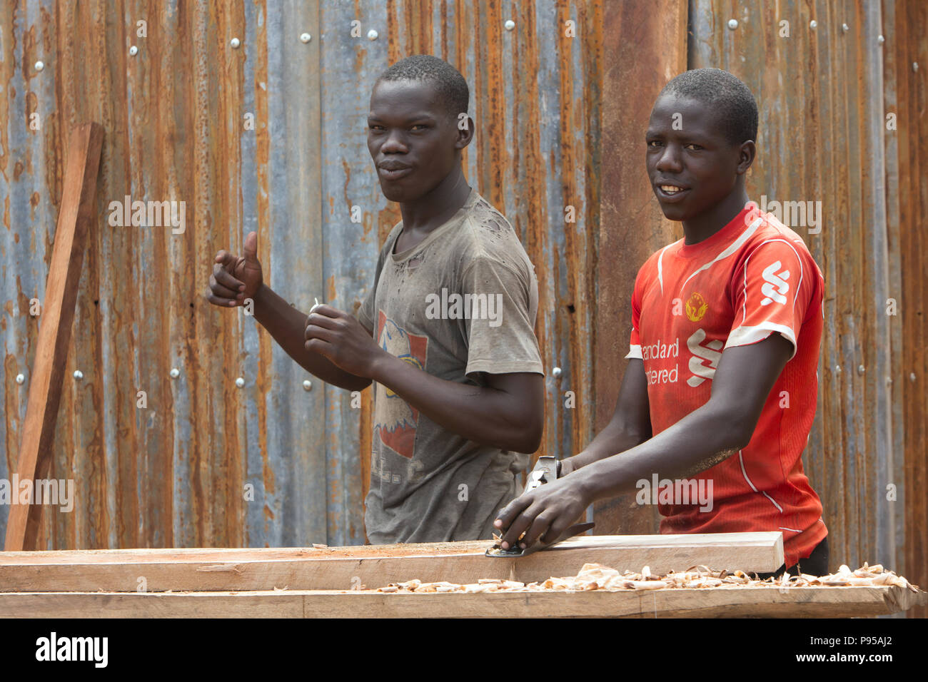 Kamdini, Uganda - A joiner is planing a wooden beam with a wooden planer. Stock Photo
