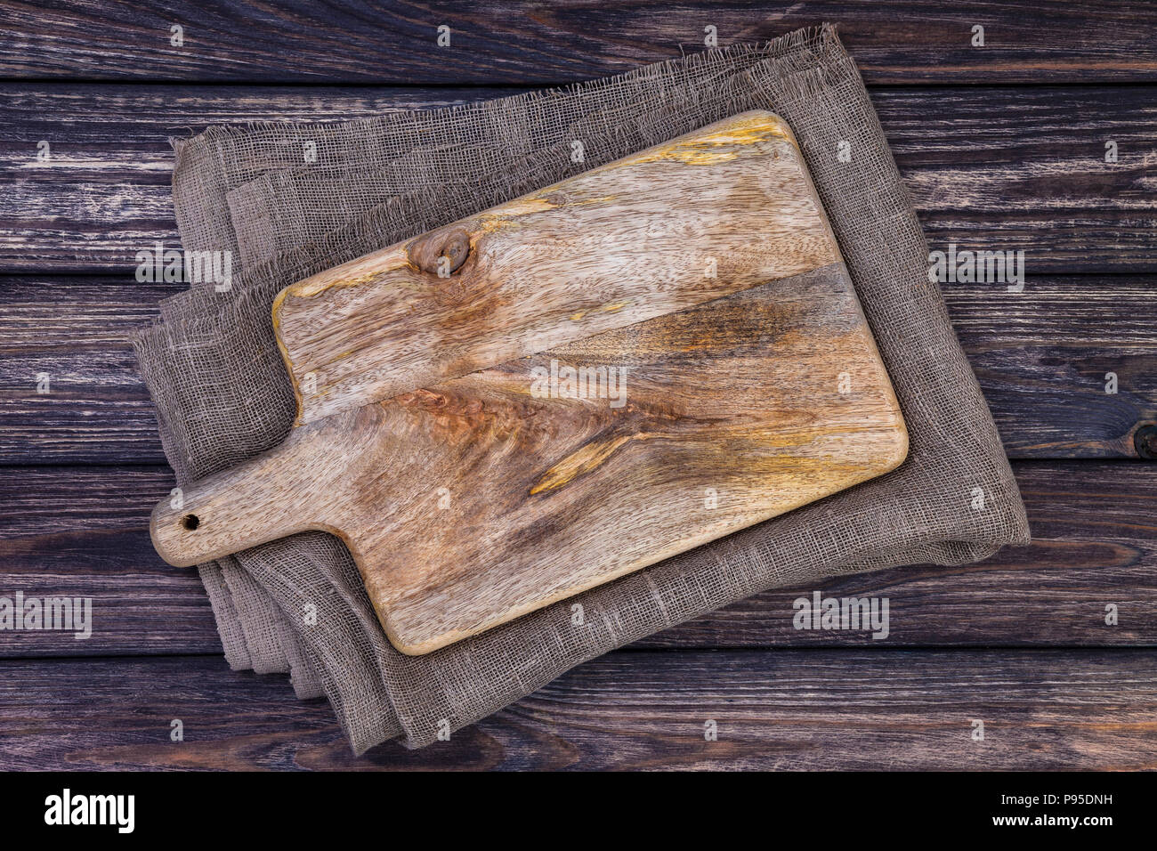 https://c8.alamy.com/comp/P95DNH/old-cutting-board-on-dark-wooden-table-top-view-copy-space-P95DNH.jpg