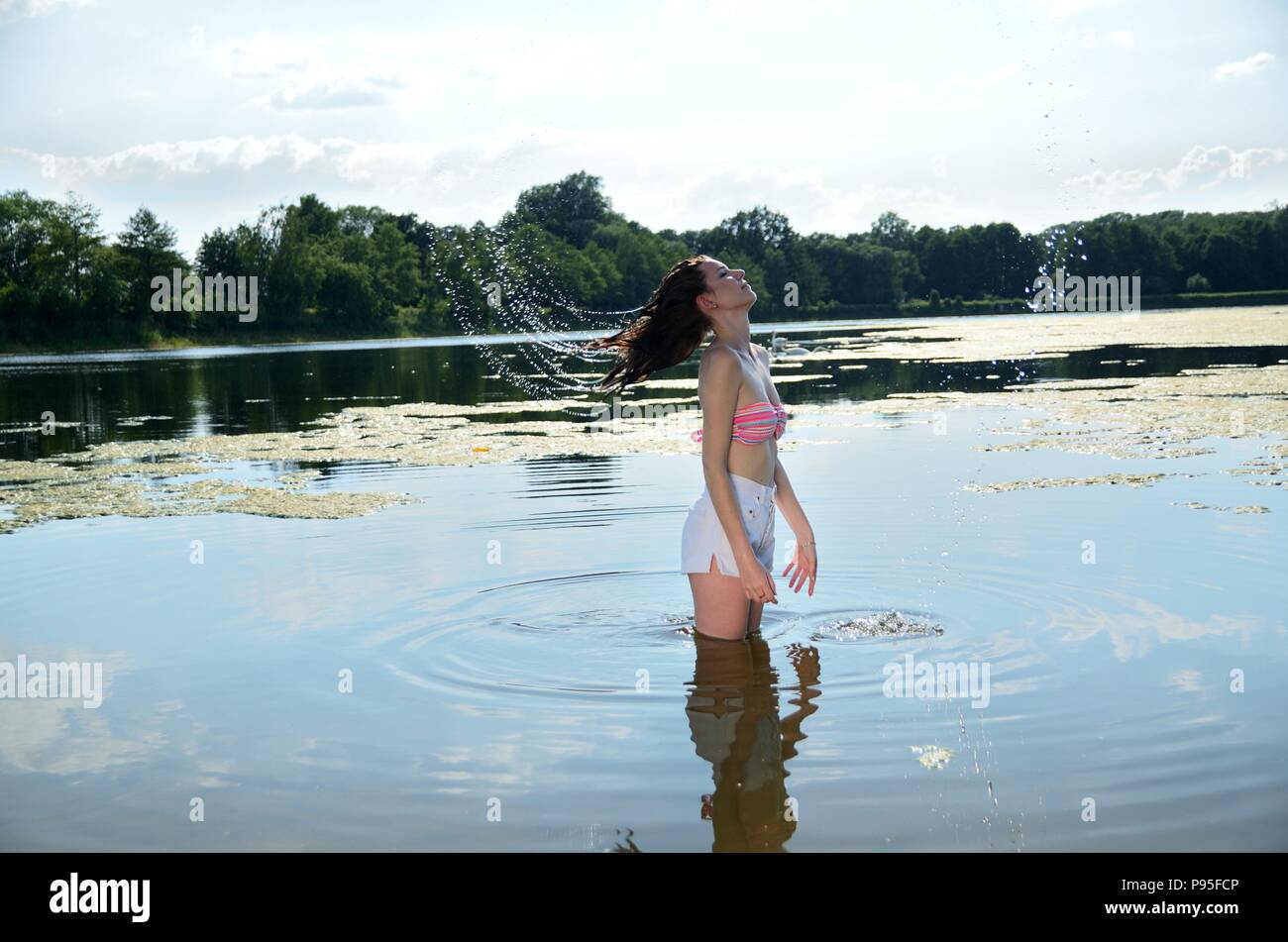 Young female model in outdoor photo session in Poland. Girl in short pants  and bikini top with wet hairs stands in lake Stock Photo - Alamy