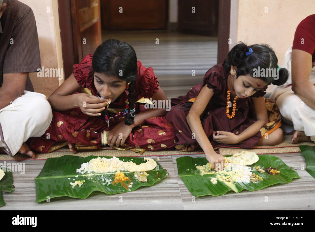 a family in kerala enjoying a feast in traditional style,sitting on floor,food served on banana leaf Stock Photo