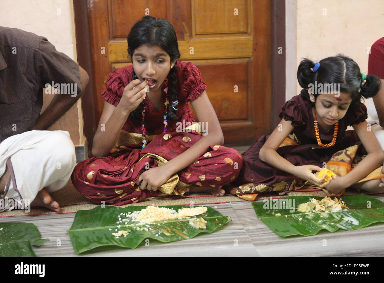 a family in kerala enjoying a feast in traditional style,sitting on floor,food served on banana leaf Stock Photo