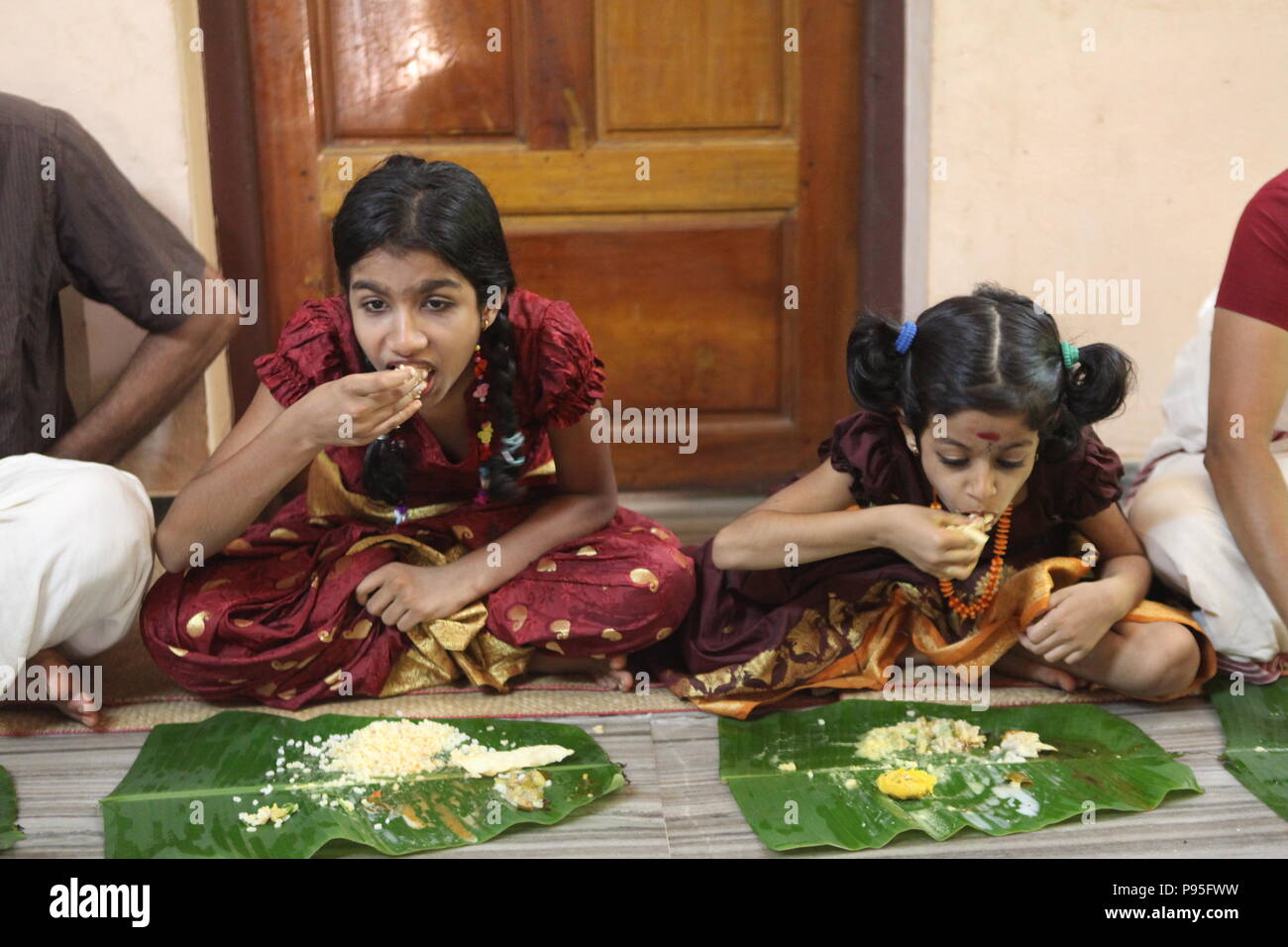 a family in kerala enjoying a feast in traditional style,sitting on floor,food served on banana leaf Stock Photo
