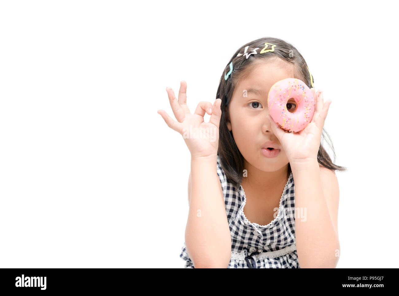 Little happy cute girl is eating donut isolated on white background. child is having fun with donut. Tasty food for kids. Funny time at home with swee Stock Photo