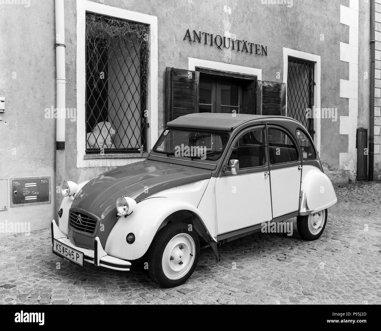 A monochrome picture of a classic Citroën 2CV car underneath an antique shop's sign in Stein an der Donau, Lower Austria Stock Photo