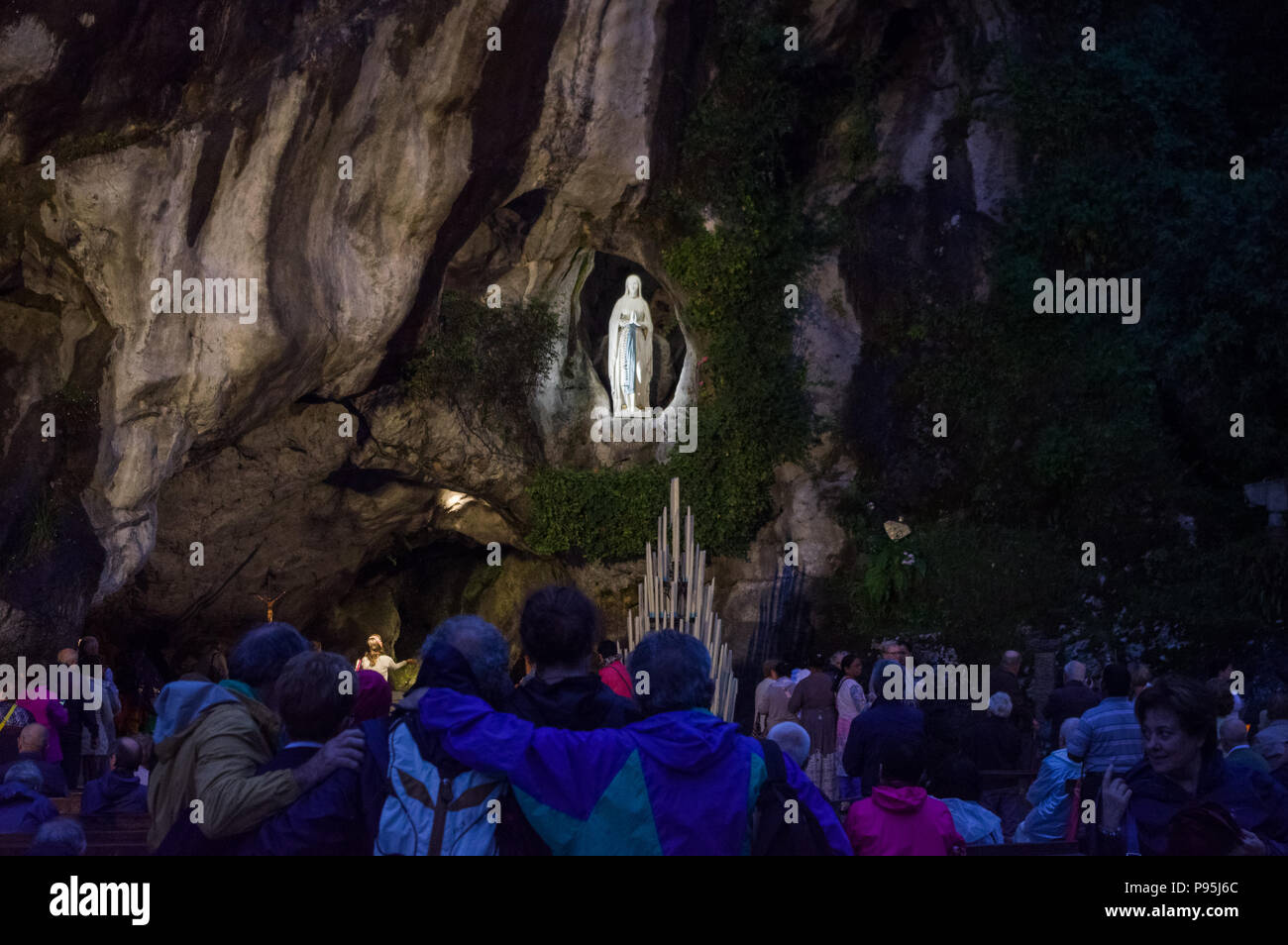 Lourdes, France (4th July 2018): Worshippers contemplating the statue of the Virgin Mary in the Grotto of Lourdes Stock Photo