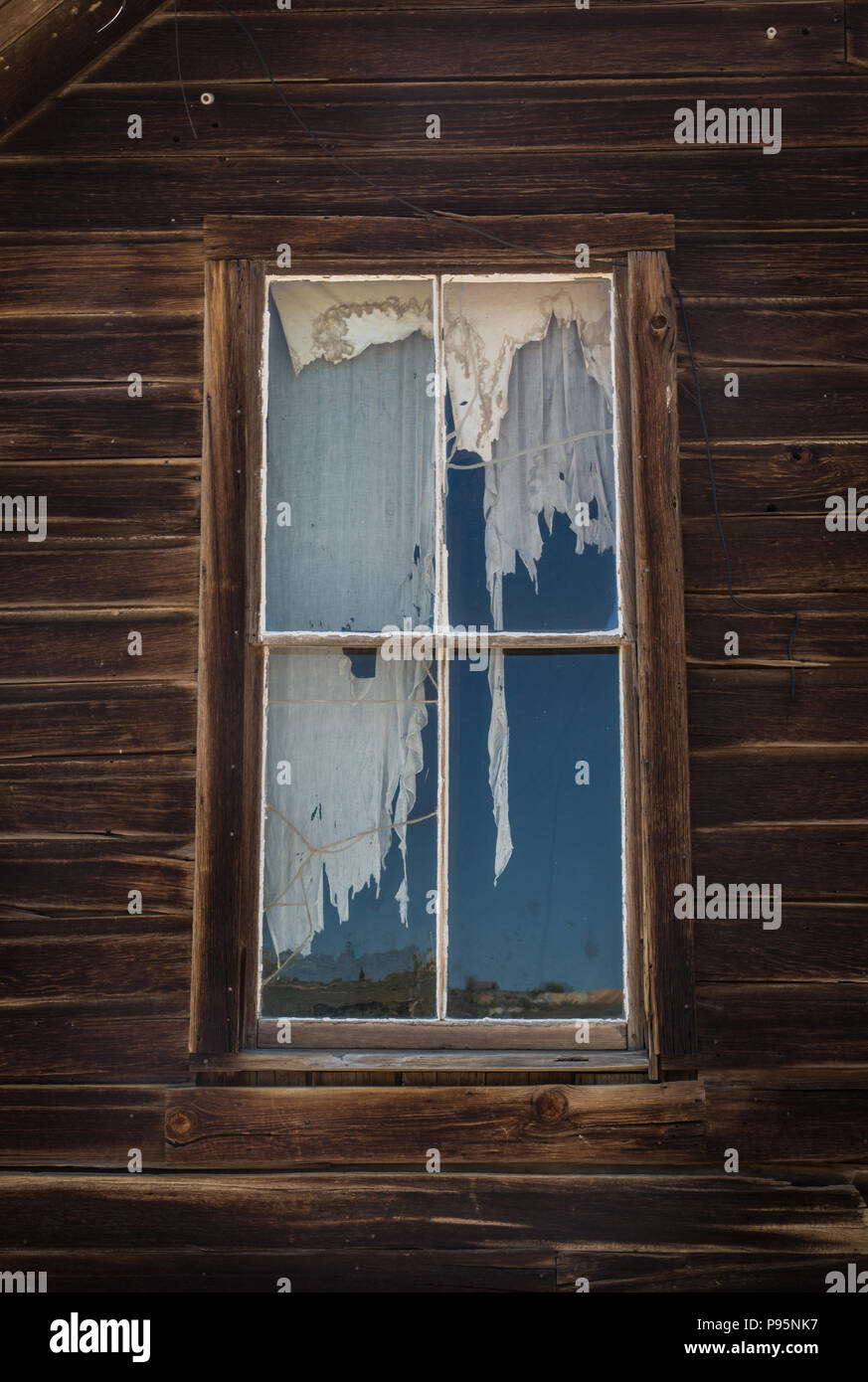 A torn curtain in a window in an abandoned home in Bodie, California, the best preserved Old West ghost town in California. Stock Photo
