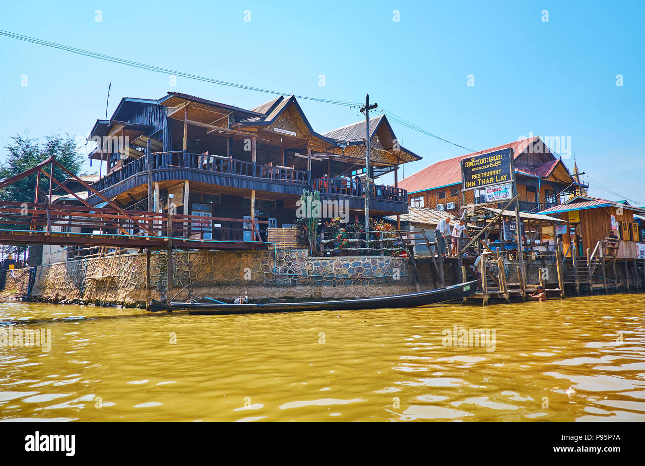 YWAMA, MYANMAR - FEBRUARY 18, 2018:  The wooden buildings with open air terraces are traditional for the villages on Inle Lake, on February 18 in Ywam Stock Photo