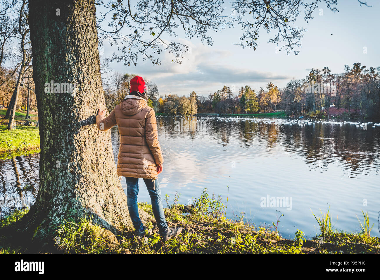 girl in a red hat wearing headphones enjoys the view of an autumn park Stock Photo
